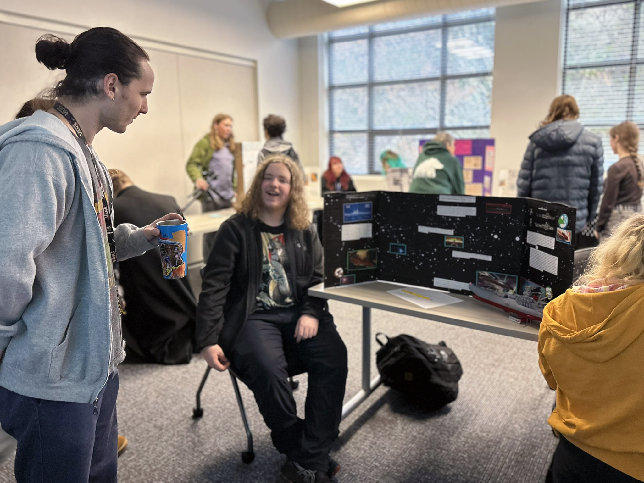 A Cedar student presenting a tri-fold poster project in class
